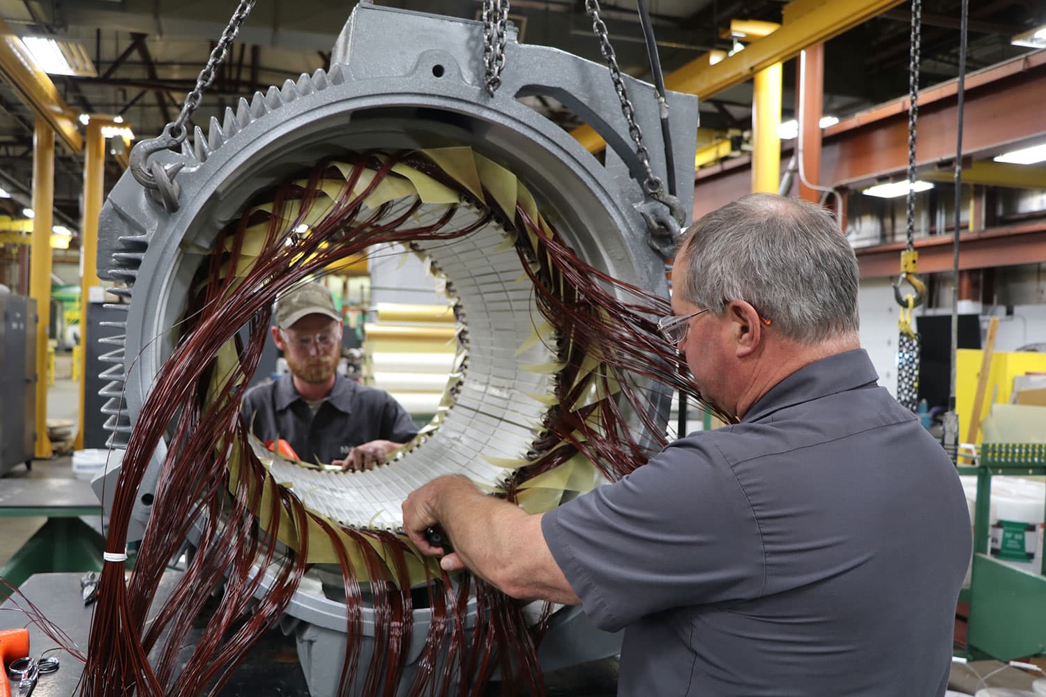 Dos técnicos rebobinando el estator de un motor industrial de gran tamaño