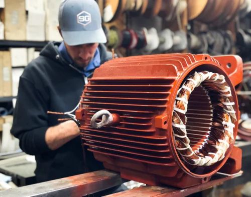 Motor industrial naranja con bobinado nuevo en el taller